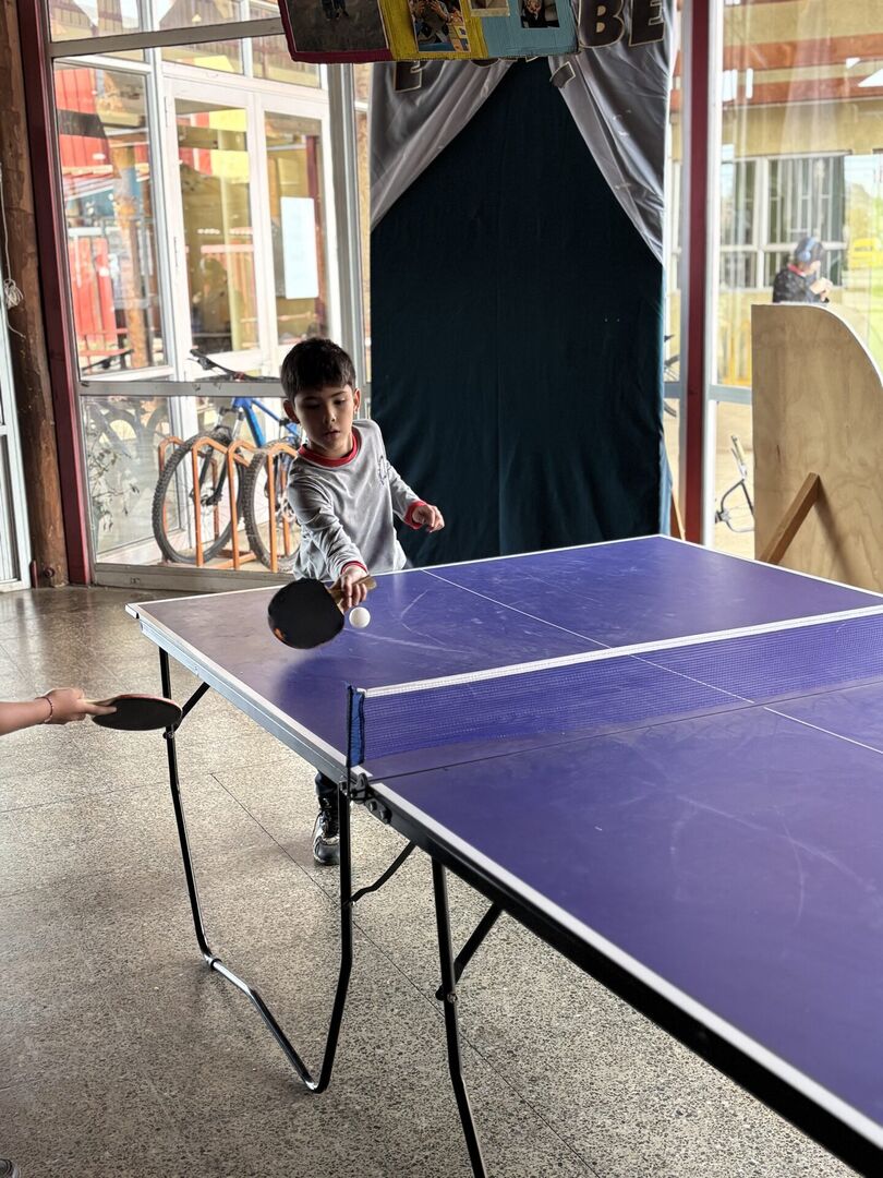Grupo de estudiantes posando con paletas de ping pong en un pasillo decorado de la Escuela Gabriela Mistral